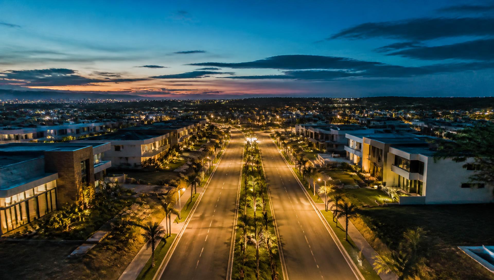Loteamento de alto padrão iluminado ao anoitecer, com avenida e infraestrutura elétrica implantada